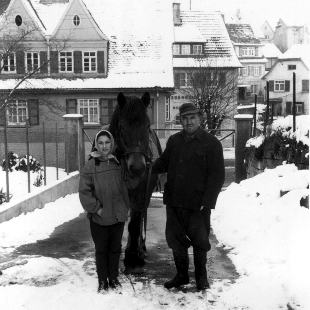 1964: Ortsobmann Erich Kern mit Tochter Martha und Pferd Schimmel in der Neckartenlinger Straße 19 (damals Hauptstraße 28) mit Blick auf das Rathaus und Milchhäusle (Quelle: Martha Kern)